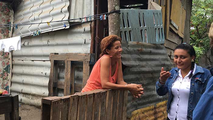 Gina (pictured right) talks with a Santa Marta community member in front of her home.